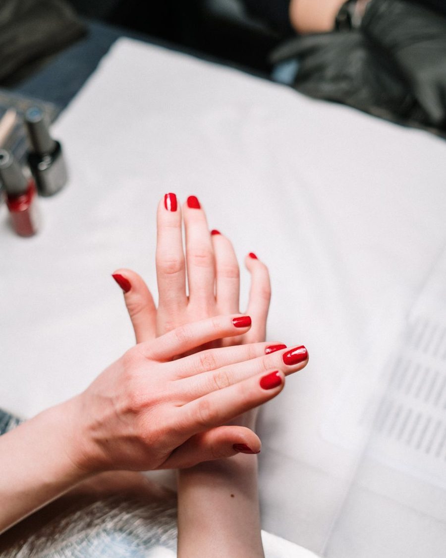 Mãos com manicure finalizada em esmalte vermelho